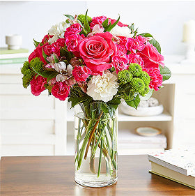 Collection bouquet of carnations and roses in a clear vase on a table