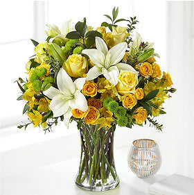 Bouquet of green, yellow, and white flowers in a clear vase