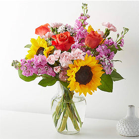 Bouquet of sunflowers and other pink and red flowers in a clear vase