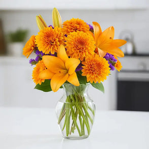 Bouquet of yellow daisies and chrysanthemums in a clear vase on a countertop
