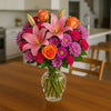 Bouquet of daisies and other flowers in a clear vase on a table