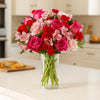 Florist's choice bouquet of pink flowers in a clear vase on a countertop