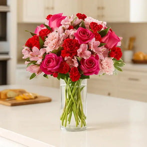 Florist's choice bouquet of pink flowers in a clear vase on a countertop