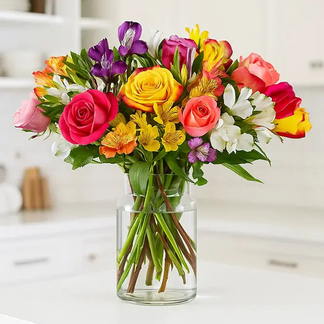 Bouquet of roses and other flowers in a clear vase on a counter